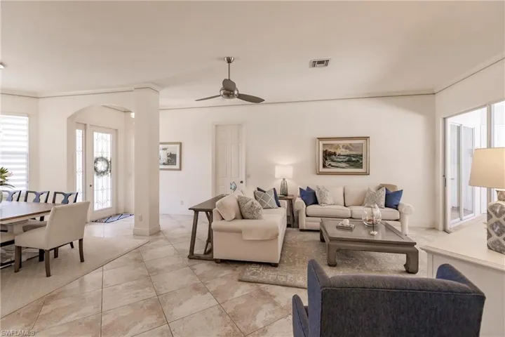 Living room with ceiling fan and light tile floors