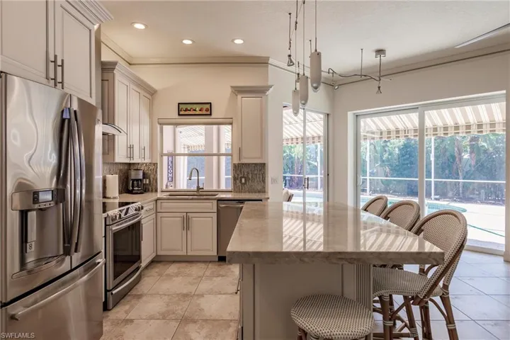 Kitchen featuring stainless steel appliances, sink, tasteful backsplash, and light tile flooring