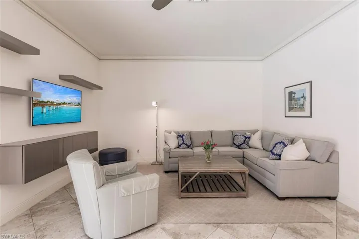 Living room featuring ornamental molding, ceiling fan, and light tile floors
