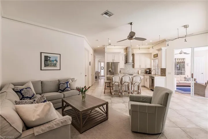 Living room featuring sink, ornamental molding, ceiling fan, and light tile flooring