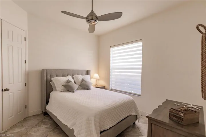 Bedroom featuring tile floors, ceiling fan, and multiple windows