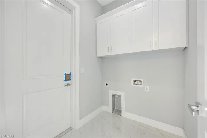 Laundry area featuring light marble finish floors, electric dryer hookup, washer hookup, and cabinet space