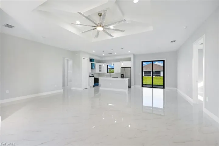 Unfurnished living room featuring light marble finish flooring, recessed lighting, a tray ceiling, and ceiling fan