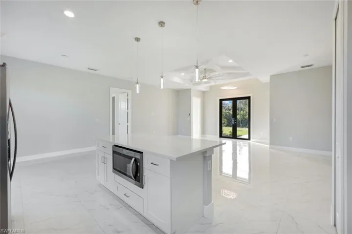 Kitchen featuring french doors, light marble finish flooring, stainless steel appliances, open floor plan, and recessed lighting