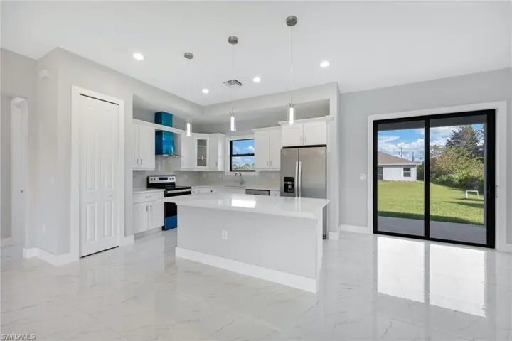 Kitchen with stainless steel appliances, white cabinetry, light marble finish floors, tasteful backsplash, and decorative light fixtures