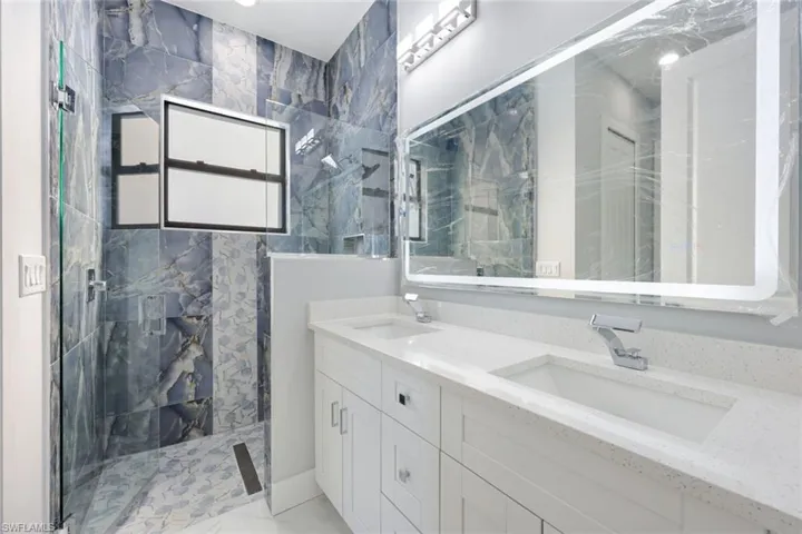Bathroom featuring a marble finish shower and double vanity