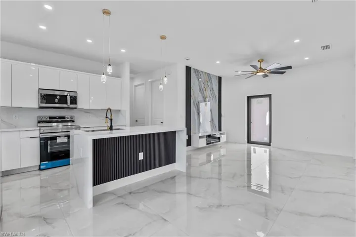 Kitchen featuring stainless steel appliances, decorative light fixtures, recessed lighting, white cabinets, and light marble finish floors