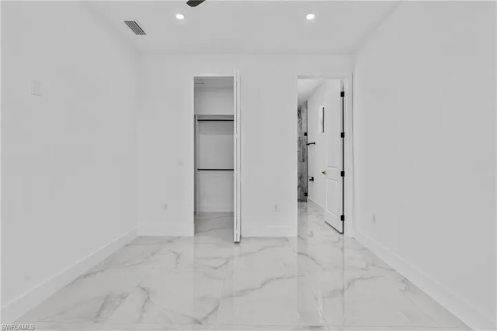 Unfurnished bedroom featuring light marble finish floors, recessed lighting, a ceiling fan, and a walk in closet