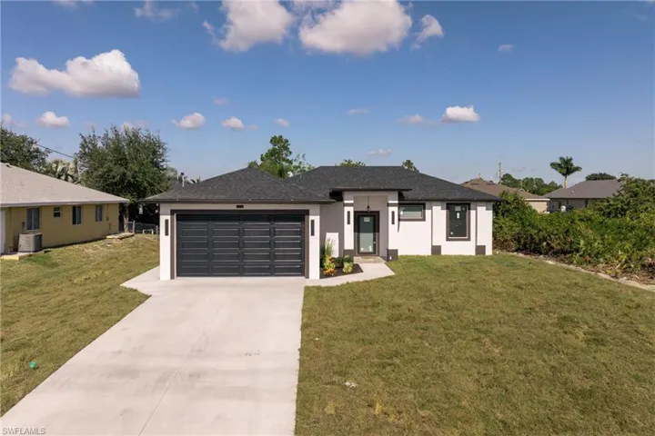 Prairie-style house featuring stucco siding, concrete driveway, an attached garage, and a front yard