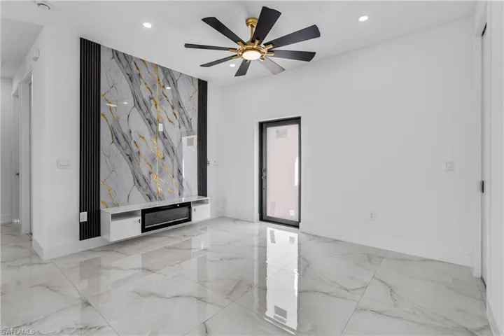Spare room featuring light marble finish floors, recessed lighting, ceiling fan, and an accent wall