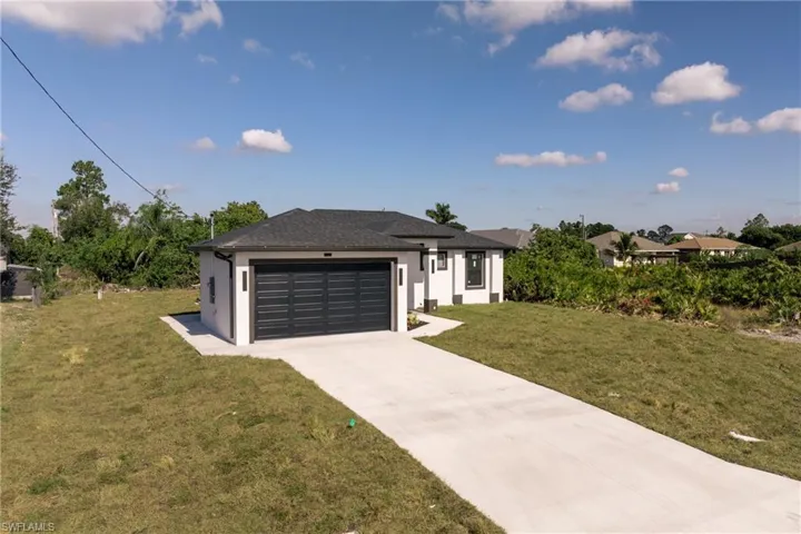 Prairie-style home featuring stucco siding, concrete driveway, and a front lawn