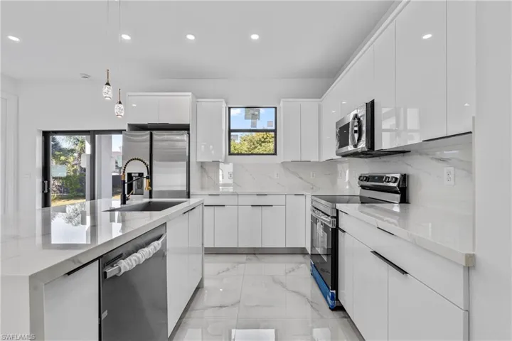 Kitchen with recessed lighting, pendant lighting, white cabinetry, stainless steel appliances, and light stone counters