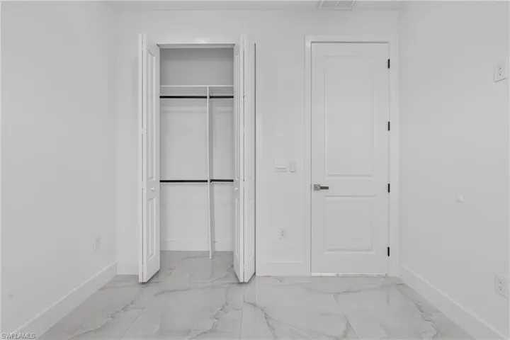 Unfurnished bedroom featuring a closet and light marble finish flooring
