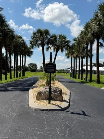 Asphalt driveway with a central landscaped island featuring a sign and decorative rocks