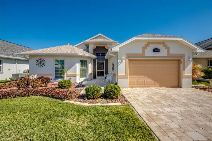 Front of home with carefully manicured landscaping, concrete curbing, and new paver driveway and entry.