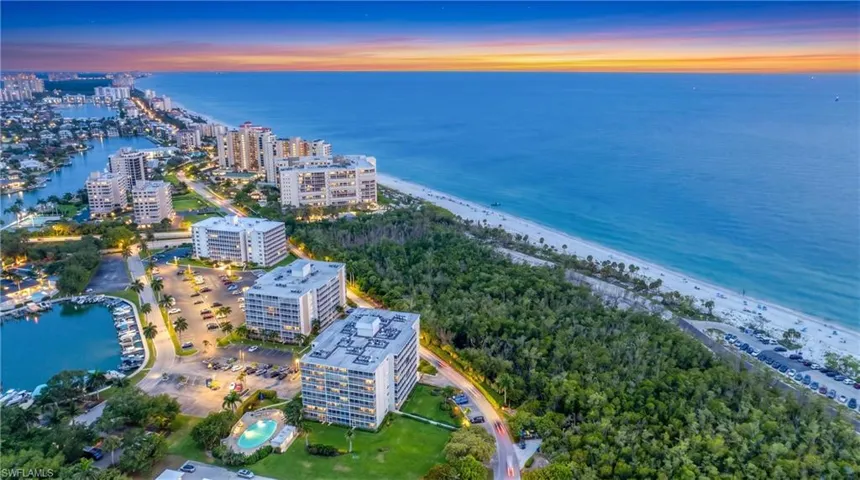 Aerial perspective of coastal residential property featuring an outdoor swimming pool, immediate proximity to the shoreline, and a landscaped grounds area