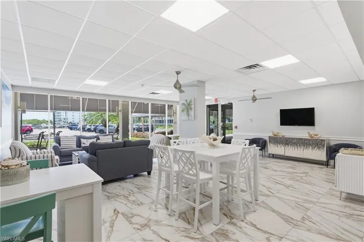 Large open-concept community room with kitchen area, seating, TV and book library.