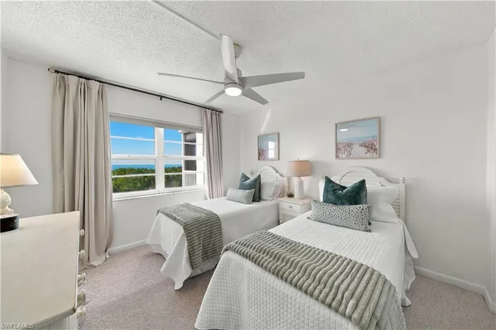 Multi-pane window with ocean backdrop, wall-to-wall carpeting, and integrated ceiling fan with light fixture