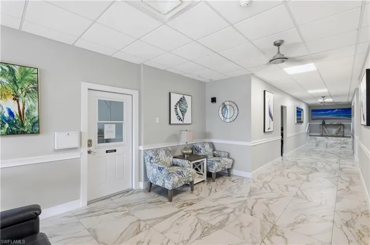 Large-format stone-style tile flooring, drop ceiling with recessed lighting, and chair rail molding