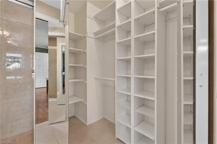 Built-in closet shelving and hanging rods with tile flooring
