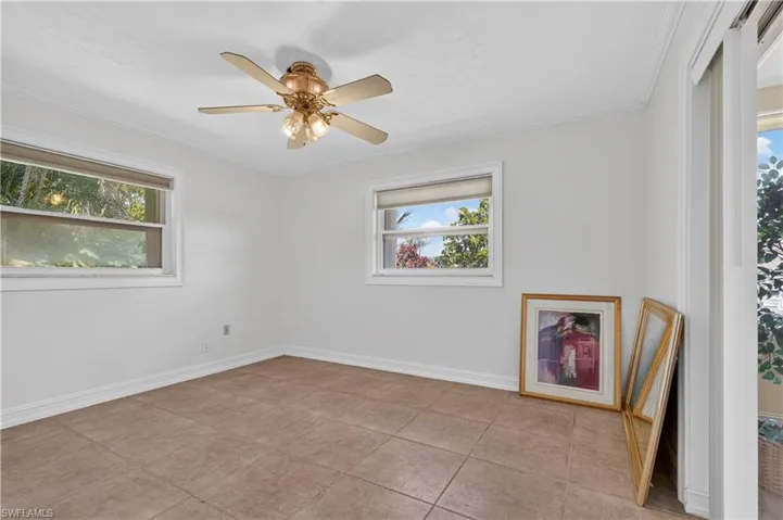Neutral wall color, ceiling fan with integrated lighting, two windows with blinds, and tile flooring