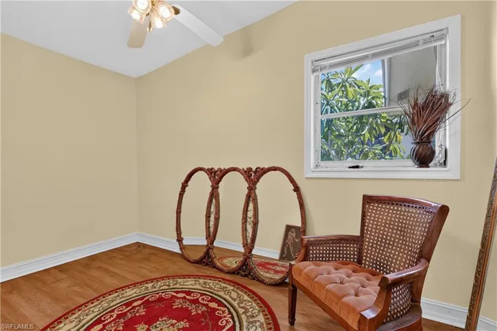Wood-finish flooring, white trim, and a ceiling fan with integrated lighting
