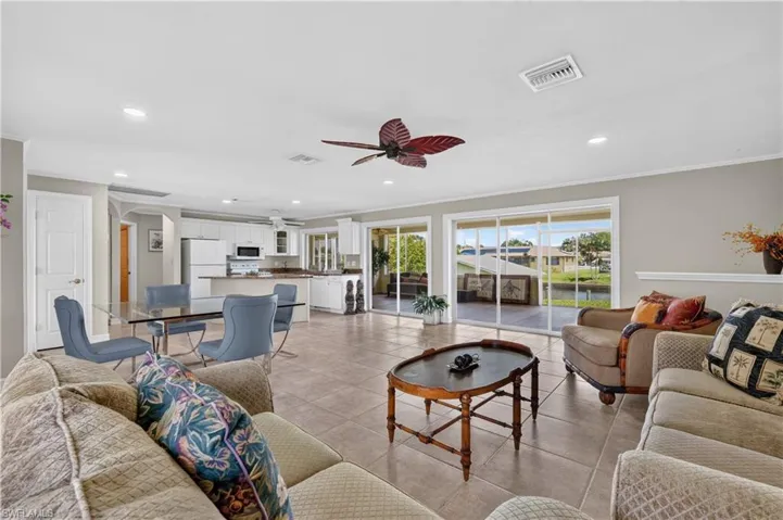 Open-concept living area featuring tile flooring, white kitchen cabinetry, a kitchen island, and sliding glass doors leading to the exterior