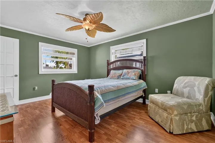 Wood-finish flooring, white trim, and a ceiling fan with palm-leaf-inspired blades