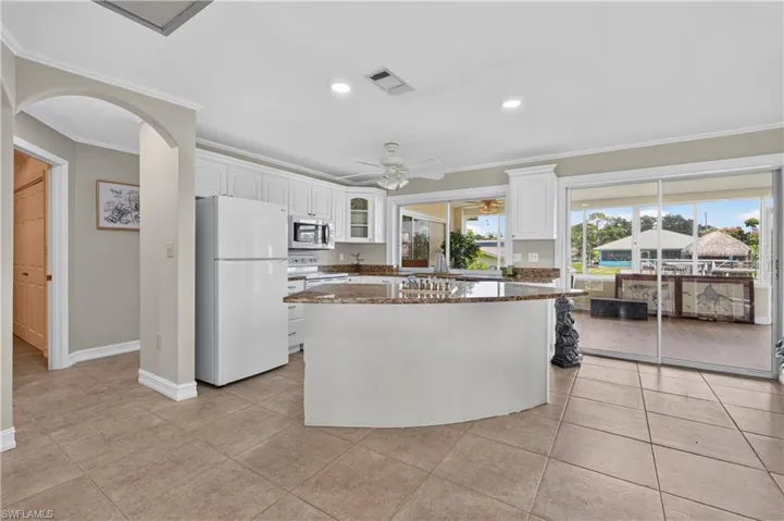 Kitchen with white cabinetry, granite countertops, tile flooring, and sliding glass doors