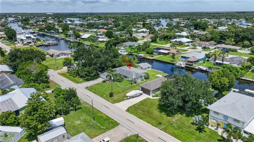 Waterfront property featuring direct canal access, mature trees, and a concrete driveway