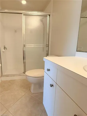 Bathroom featuring vanity, light tile patterned floors, and a shower stall