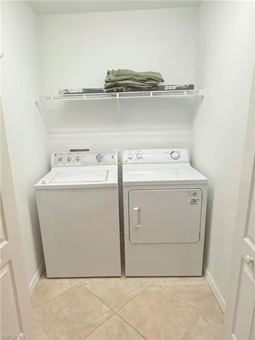 Laundry room with light tile patterned floors and washing machine and clothes dryer