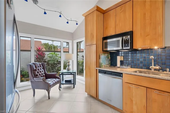 Kitchen with decorative backsplash, sink, light stone countertops, appliances with stainless steel finishes, and plenty of natural light