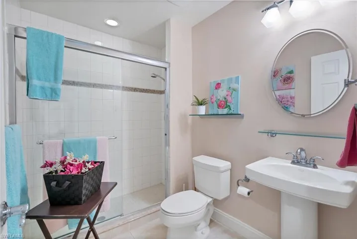 Bathroom featuring sink, tile patterned floors, a shower with door, and toilet