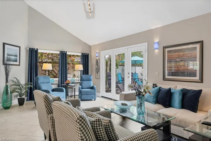 Living room featuring high vaulted ceiling, light tile patterned floors, and french doors