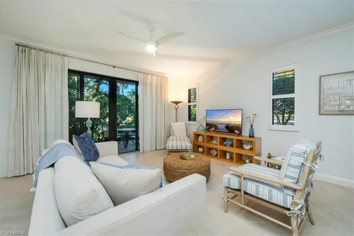 Living room featuring ceiling fan, plenty of natural light, and ornamental molding