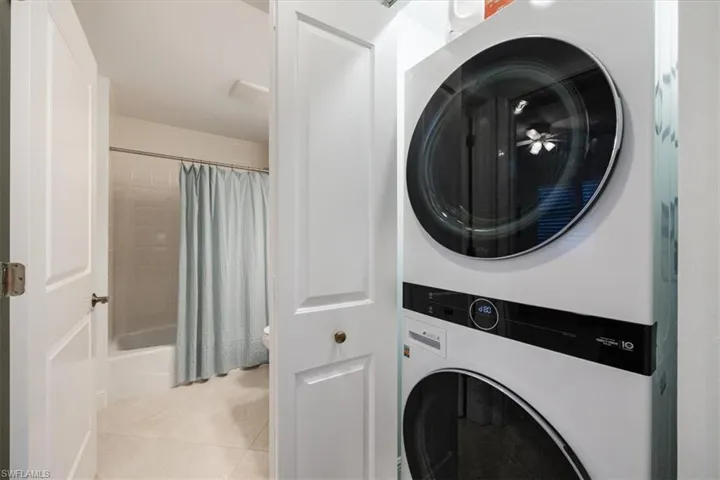 Laundry area featuring stacked washer and dryer and light tile patterned flooring