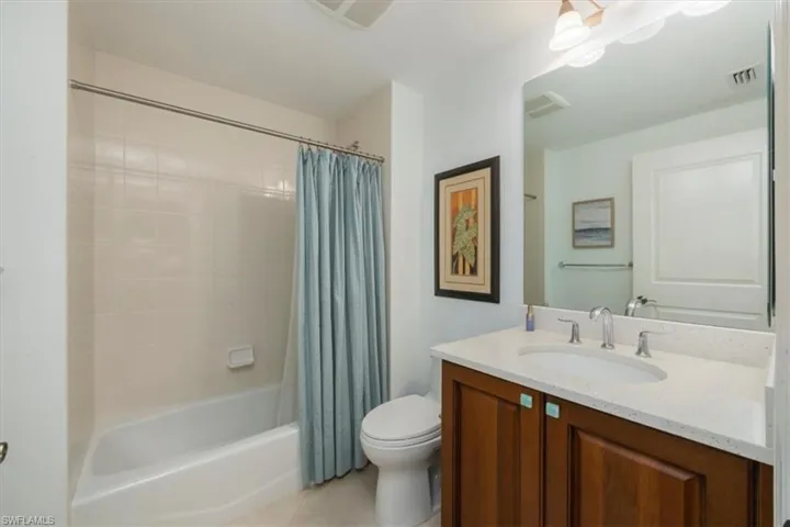 Bathroom with vanity, shower / bath combo with shower curtain, and light tile patterned floors
