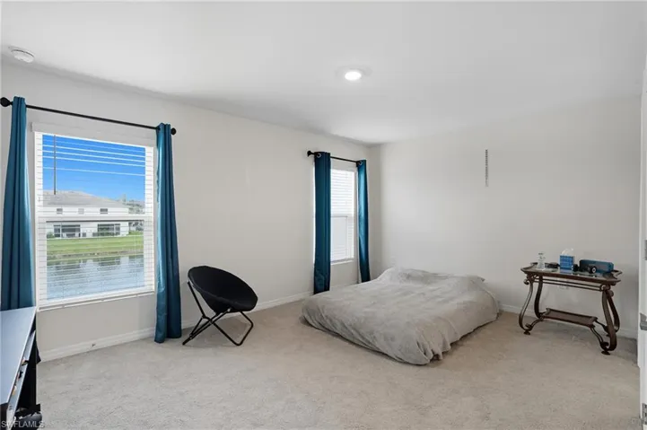 Bedroom featuring light carpet and a water view