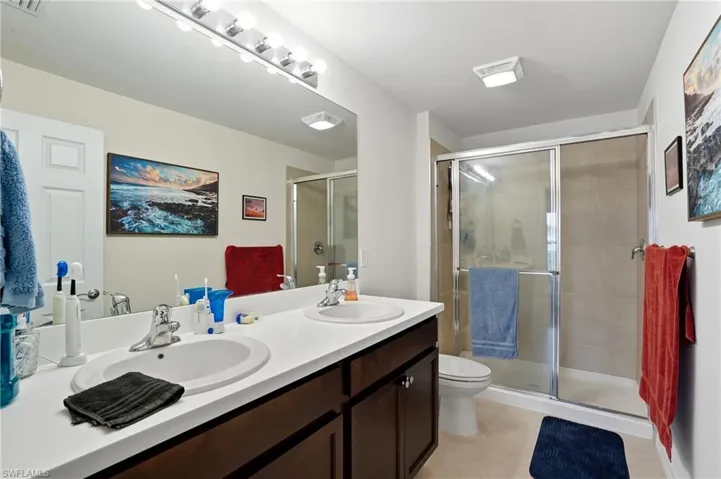Full bath featuring a shower stall, light tile patterned floors, and double vanity