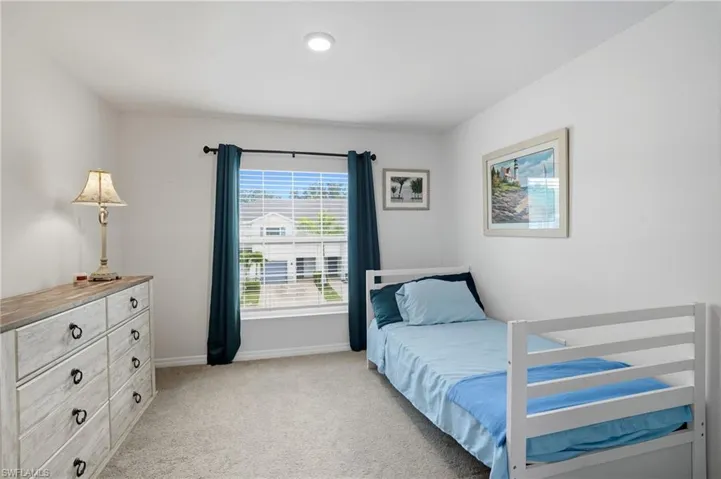 Bedroom featuring light carpet and baseboards