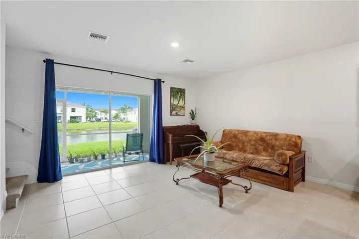 Living area with stairs, a water view, and light tile patterned flooring
