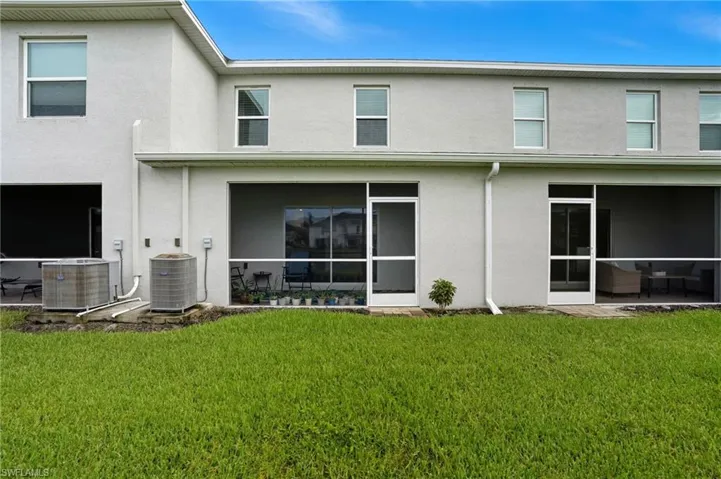Rear view of house with stucco siding, a yard, and a sunroom