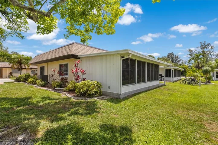 View of home's exterior with the lovely sunroom and a nice yard
