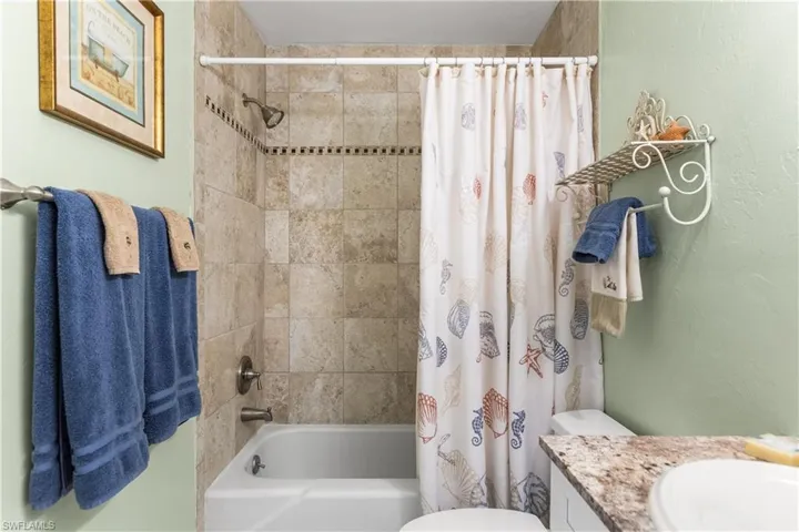 Full bathroom with shower / bathtub combination with curtain, vanity, and toilet