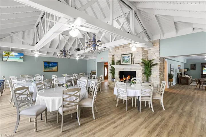 Beautifully remodeled community dining room with high vaulted ceiling, a stone fireplace, hardwood / wood-style flooring, and ceiling fan