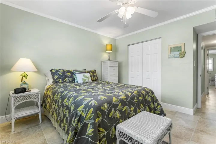 Bedroom with ornamental molding, a closet, light tile flooring, and ceiling fan