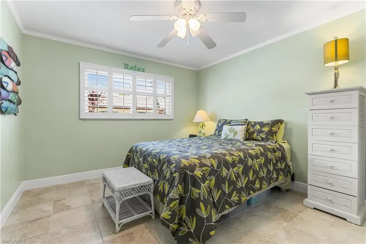 Tiled bedroom with ceiling fan and ornamental molding