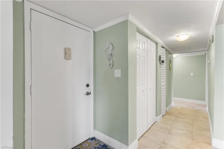 Hall featuring ornamental molding and light tile floors