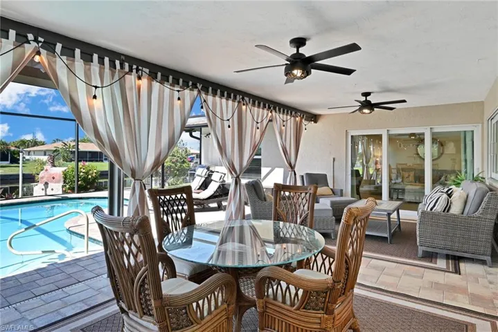 View of patio featuring outdoor dining space, a ceiling fan, an outdoor living space, glass enclosure, and an outdoor pool